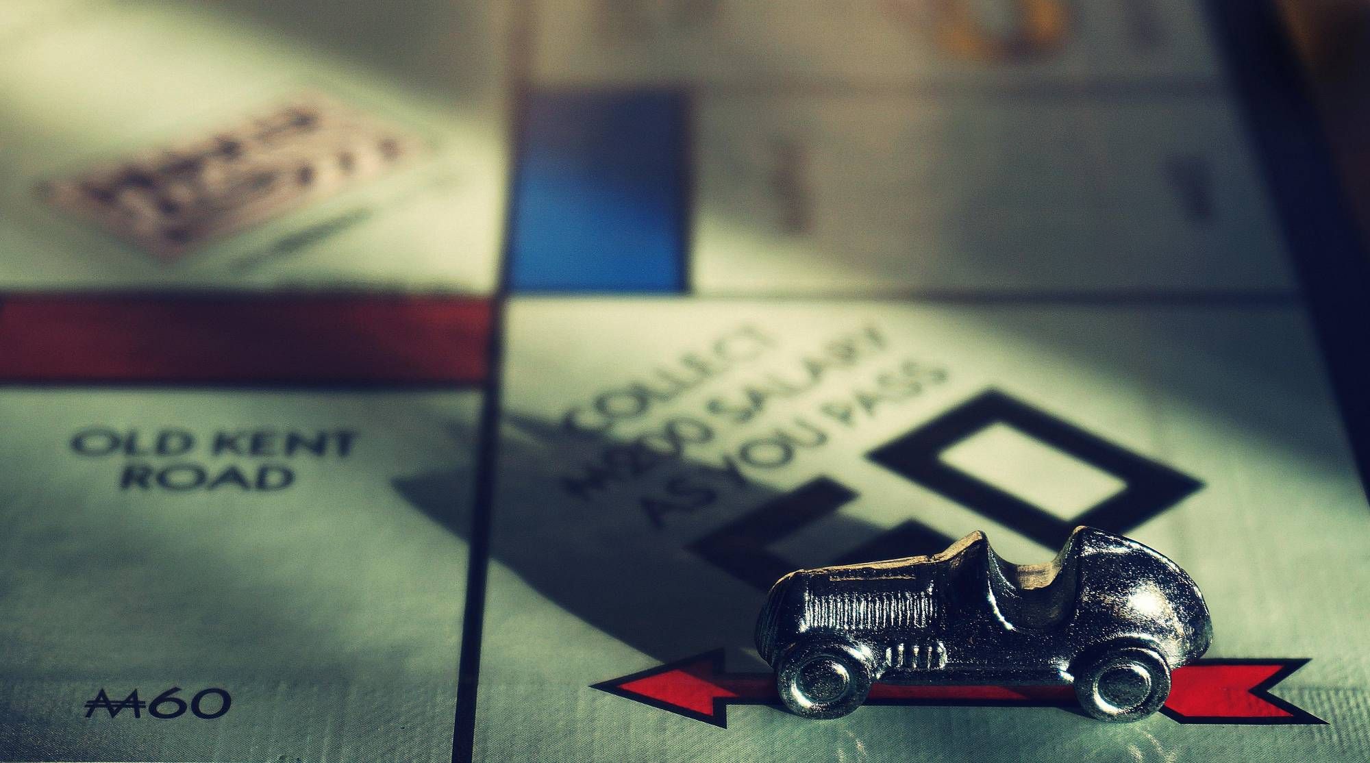 Monopoly board with a silver car token on the "GO" space, illuminated by dramatic lighting for the financing page at Mountain Crest Reserve