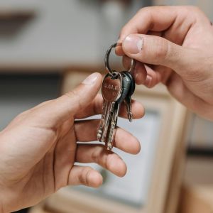 Close-up of one hand passing a set of keys to another hand indoors.