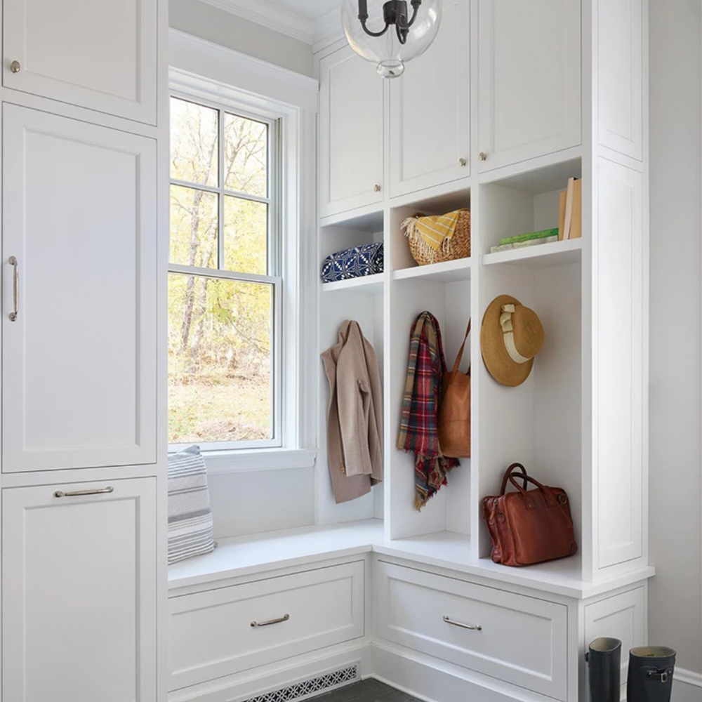 White mudroom with storage cubbies, a window seat, and a hanging light fixture. Coats and shoes are neatly arranged at Mountain Crest Reserve 