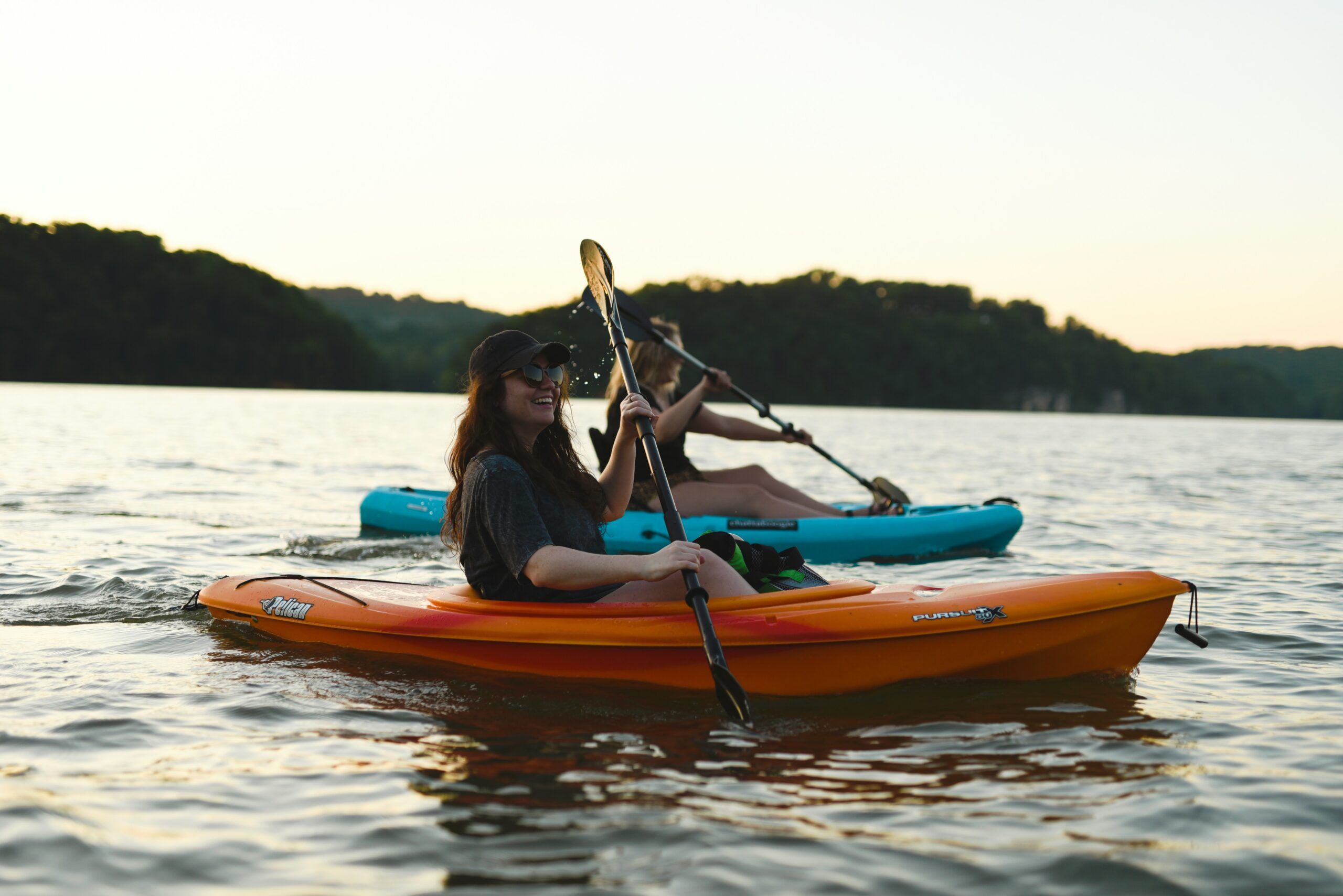 Two people kayaking on a calm lake at sunset, with trees in the background at Mountain Crest Reserve.