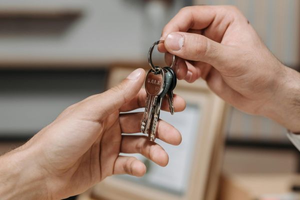 Close-up of one hand passing a set of keys to another hand indoors.