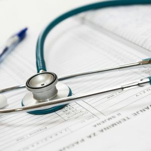 Stethoscope and pen on medical documents with charts and text.