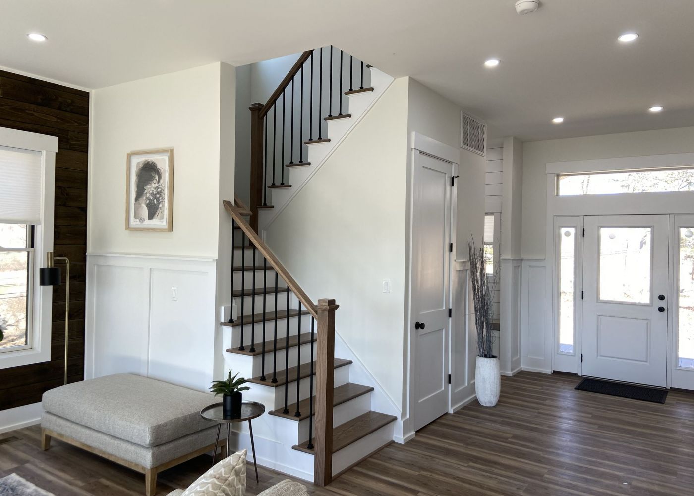 Open living room with a staircase, modern furniture, and a large window near the front door.