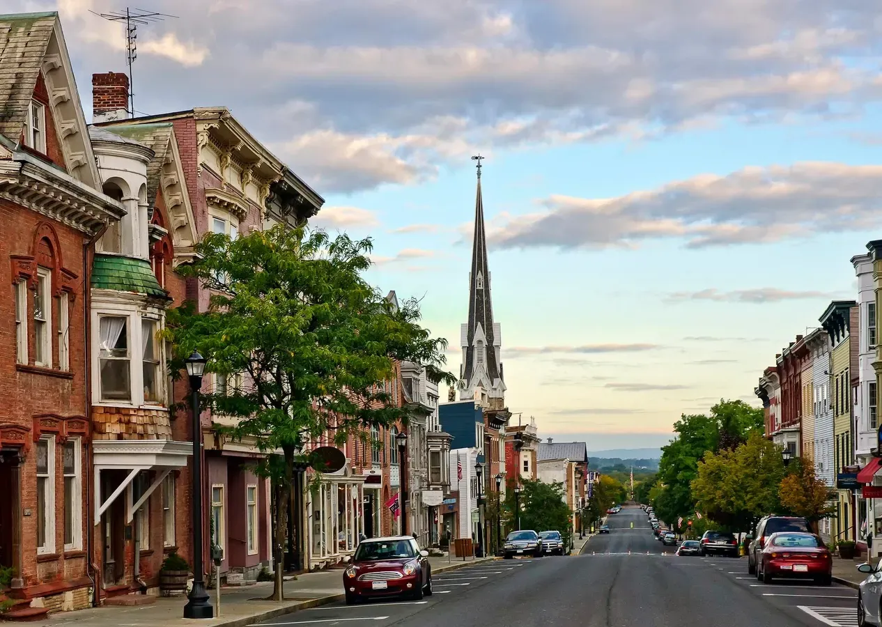 Street view of a small town with historic buildings, parked cars, and a church spire under a partly cloudy sky at Mountain Crest Reserve.